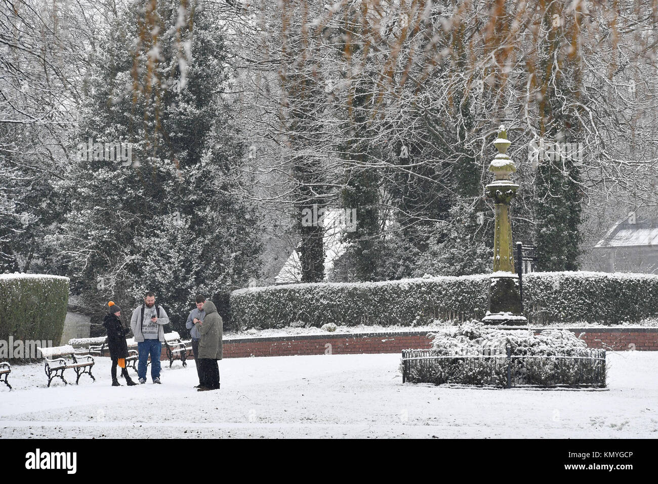 Un groupe de personnes regardant leurs téléphones, dans la neige couverts Stamford Park en Ashton-Under-Lyne, Greater Manchester, comme de vastes perturbations s'attend à ce que la neige continue de tomber dans de vastes parties du Royaume-Uni, avec les prévisionnistes avertissement certaines communautés pourraient être coupées car les températures chutent. Banque D'Images