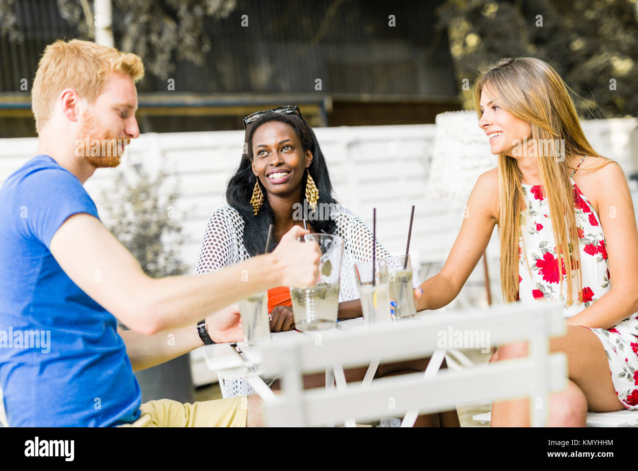 Les jeunes et happy friends sitting parle à une table Banque D'Images