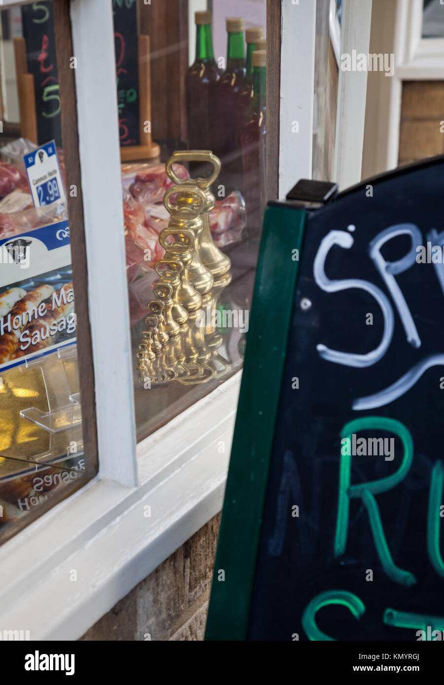 Une série de laiton à l'ancienne poids impériale sur l'affichage dans la fenêtre d'une ville de marché boutique butchers Banque D'Images