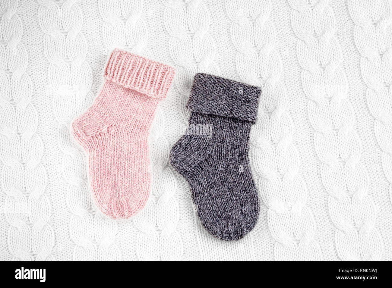 Une paire de couleur différente de mignons petits tricots de cachemire  chaussettes bébé nouveau-né sur un fond de laine blanche Photo Stock - Alamy