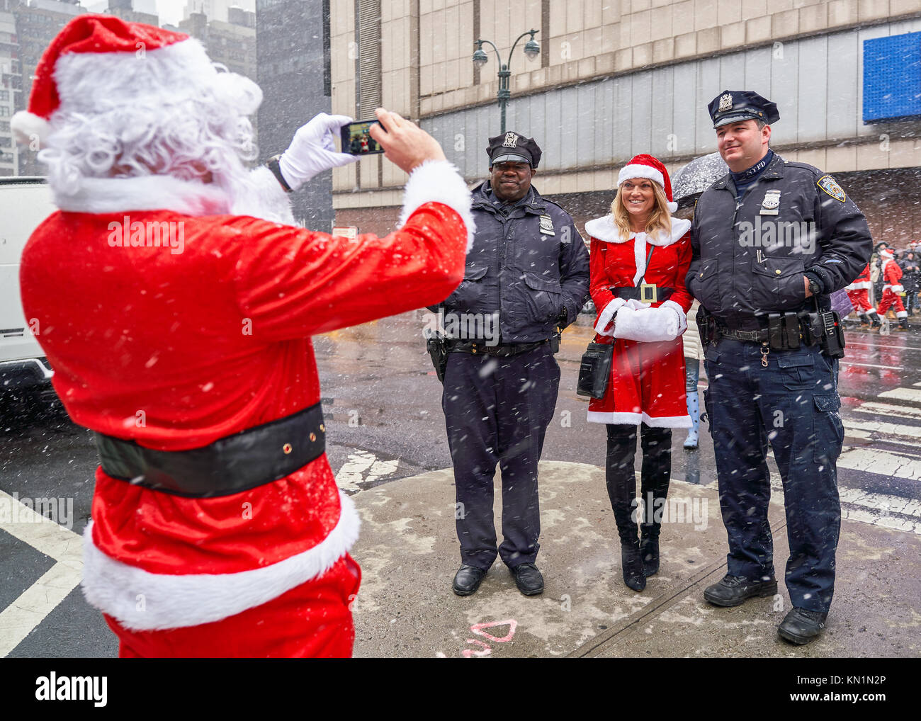 New York, États-Unis, 9 déc 2017. Une femme habillée en père Noël a sa photo prise par un autre Santa à côté de New York City Police garde la "fête" antacon foule qui se sont réunis au centre-ville malgré la tempête de neige. Photo par Enrique Shore/Alamy Live News Banque D'Images