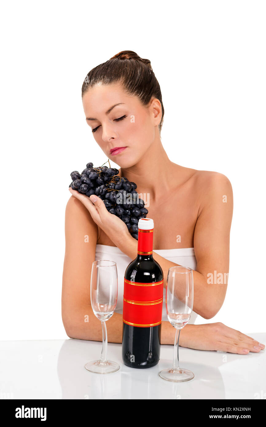 Une femme tenant les raisins frais, sur la table deux verres et une bouteille de vin Banque D'Images
