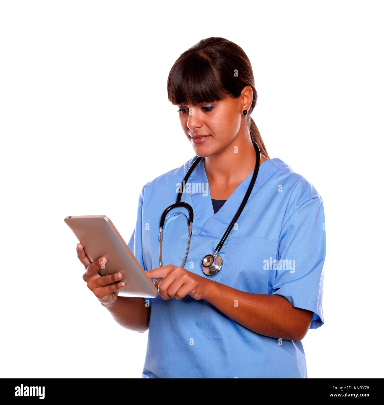 Portrait d'une jeune infirmière professionnelle en utilisant sa tablette sur l'uniforme bleu avec un stéthoscope sur fond isolé. Banque D'Images