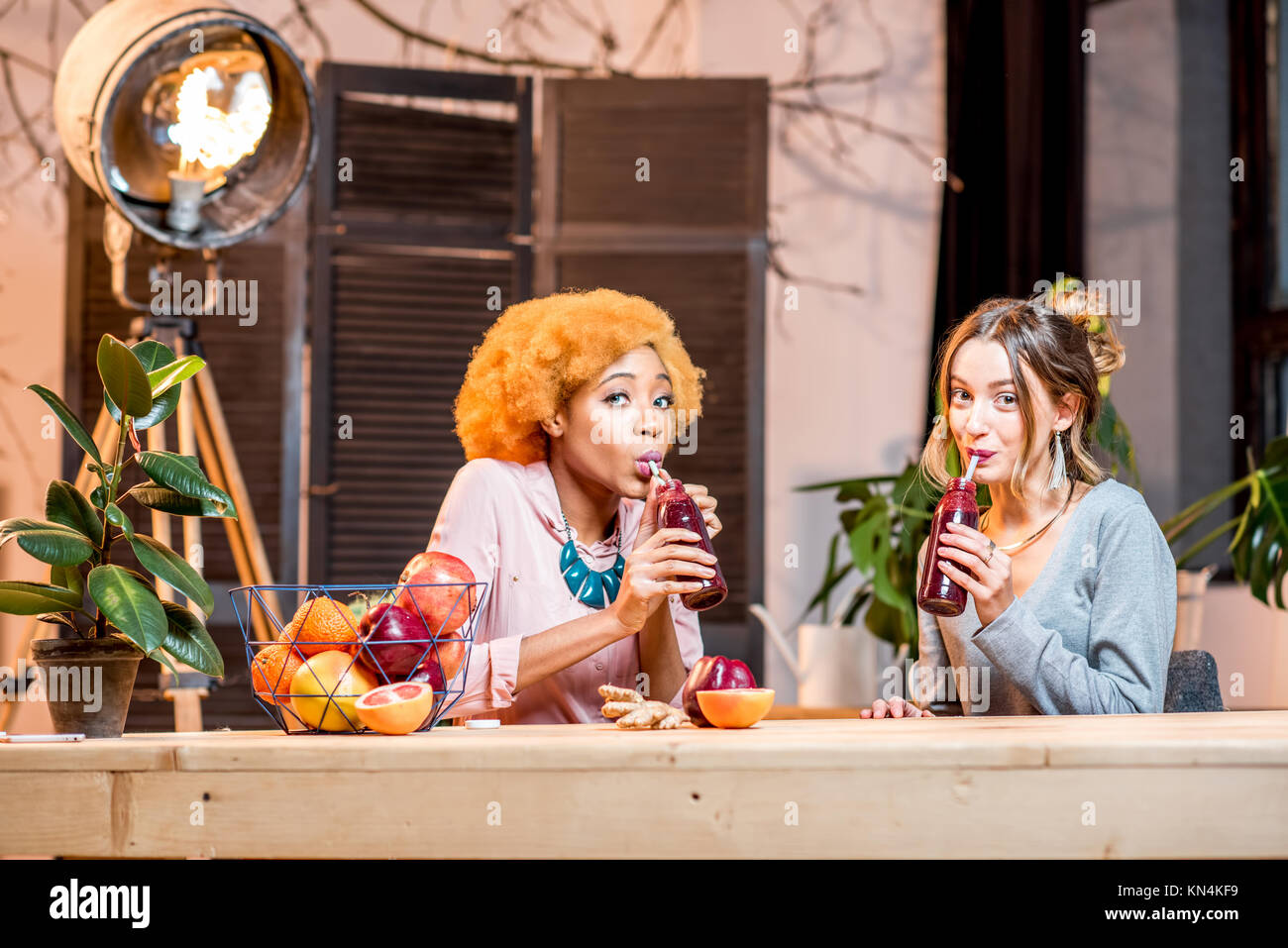 Les femmes avec des fruits et des smoothies à la maison Banque D'Images