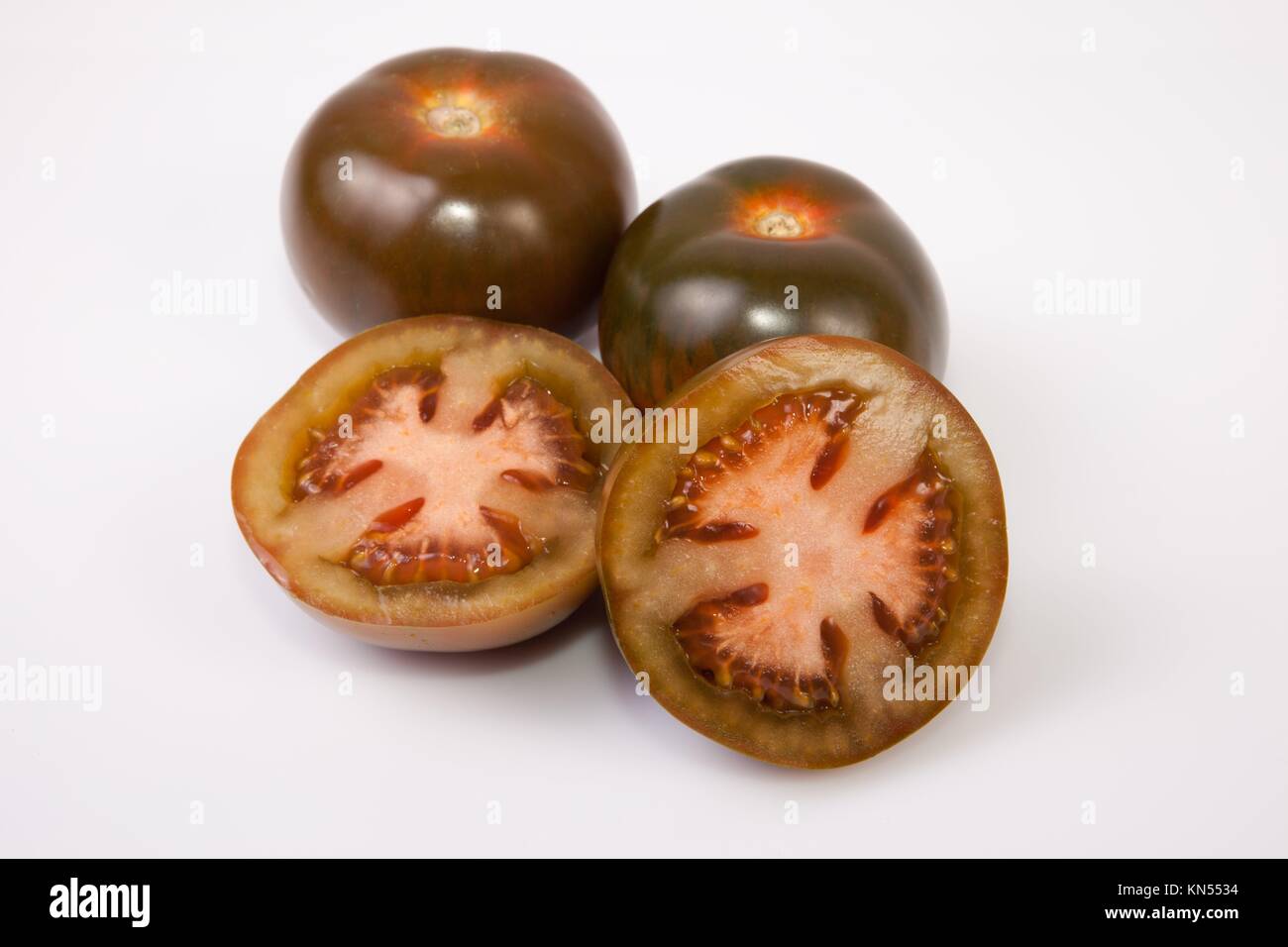 Les tomates kumato vert foncé, entières ou coupées en tranches. Plus isolé sur fond blanc. Banque D'Images