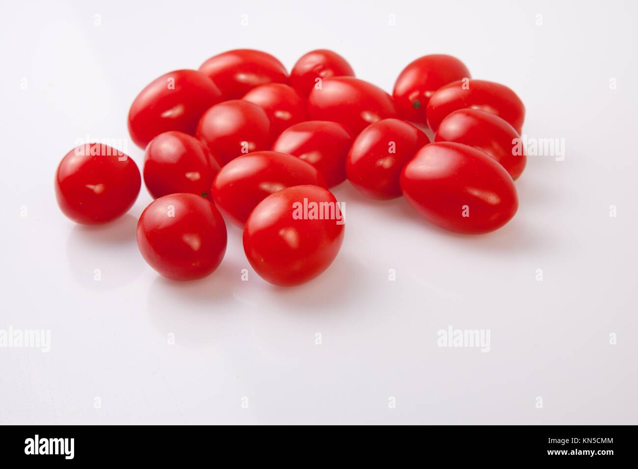 Poignée de tomates cerise rouge brillant. Plus isolé sur fond blanc. Banque D'Images
