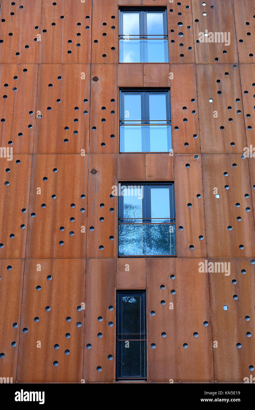 Fenêtres avec balcon en façade de l'immeuble avec des plaques de métal rouillé à trous ronds Banque D'Images