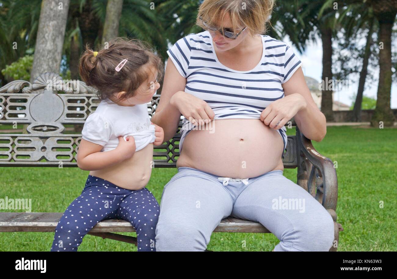 Bébé fille jouant avec sa mère ventre. Ils montrent leur ventre. Banque D'Images