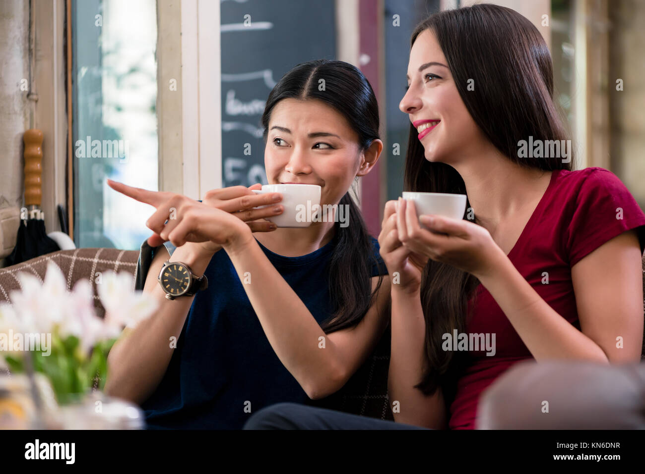 Jeune femme bavarde pointant tout en restant assis dans un café Banque D'Images