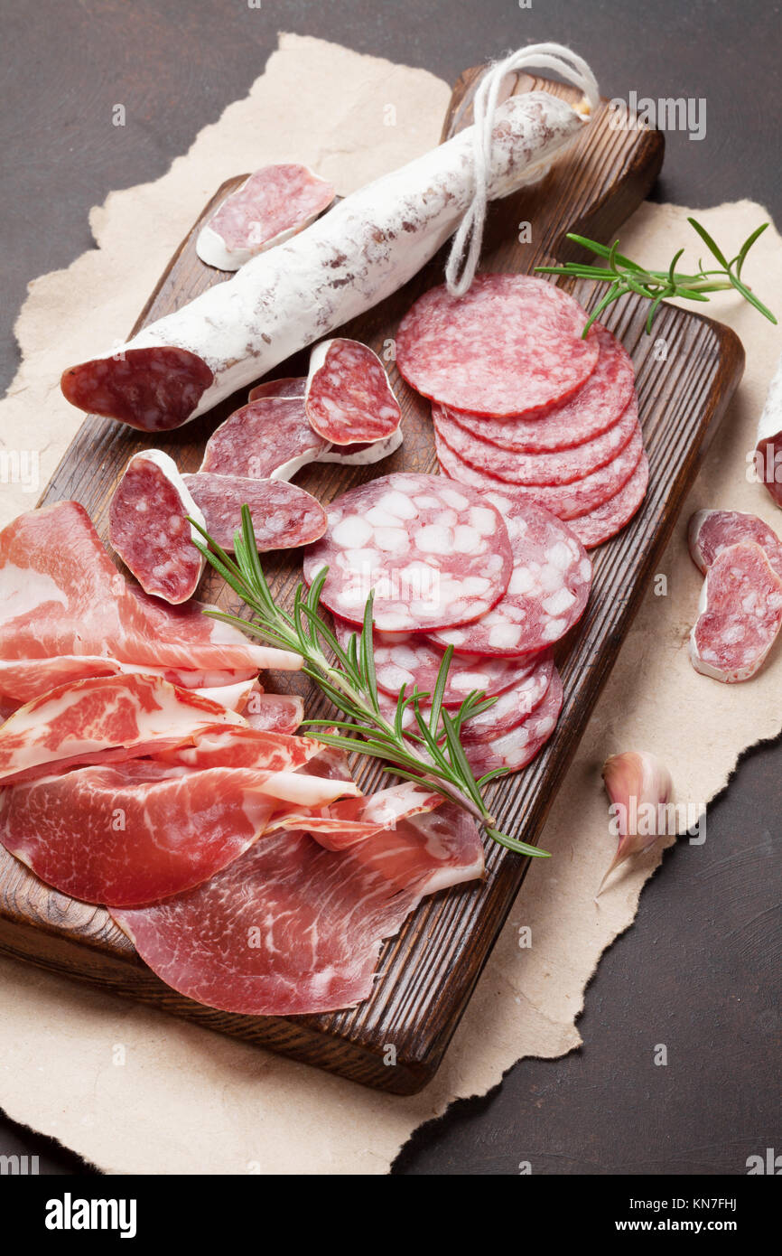 Tranches de salami, jambon, saucisses, jambon, bacon. Plateau d'antipasto de viande sur table en pierre Banque D'Images