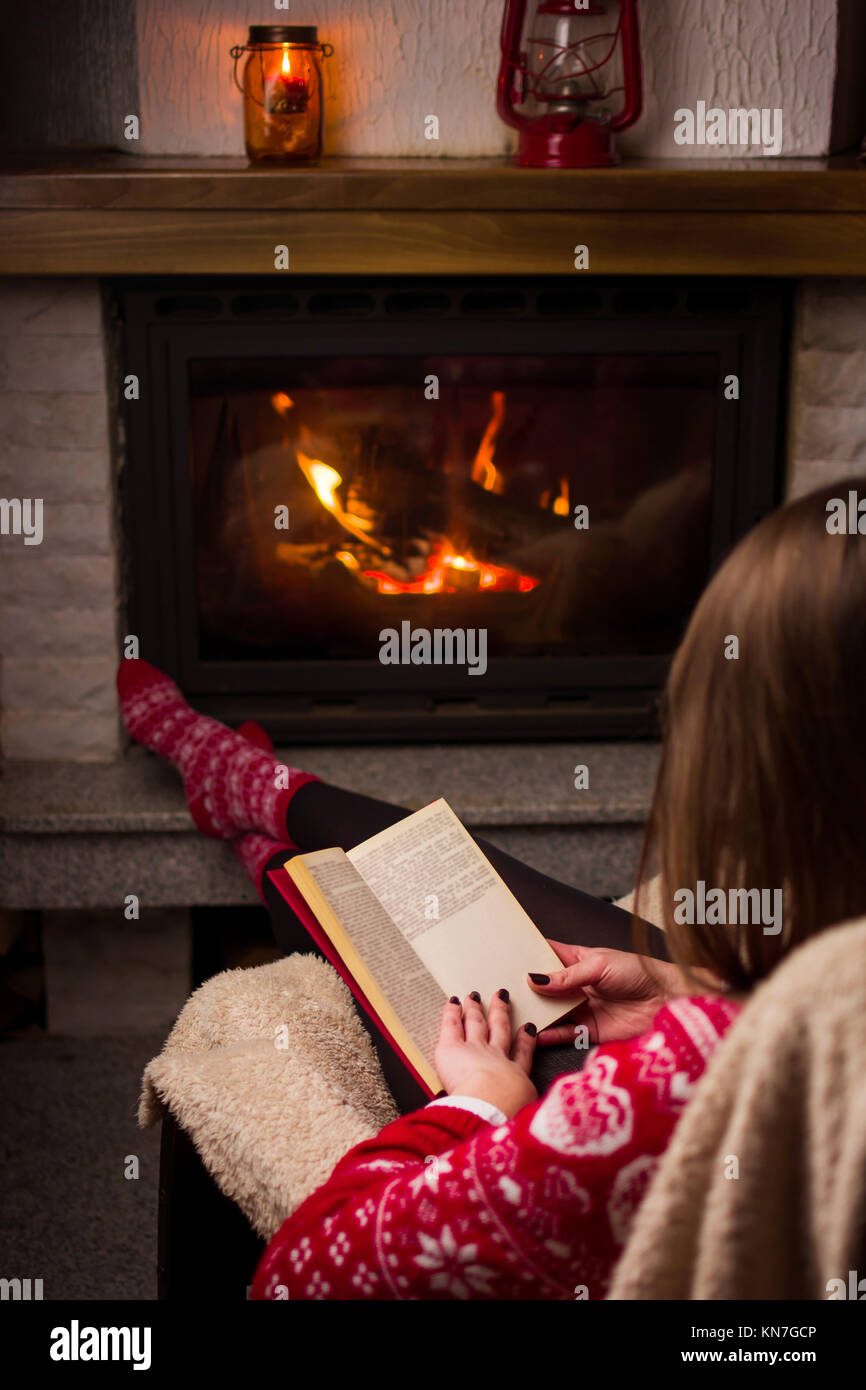 Girl reading par le feu. Vie d'hiver douillet à l'intérieur Banque D'Images