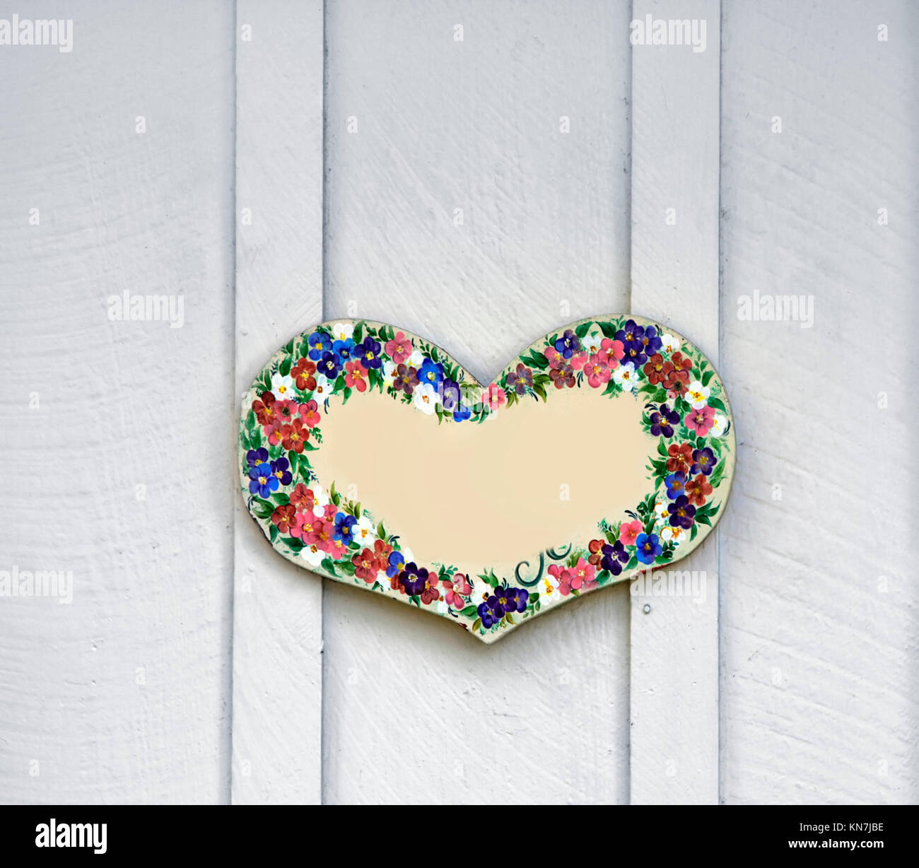 Coeur en bois peint avec des fleurs, comme décoration sur une porte en bois Banque D'Images