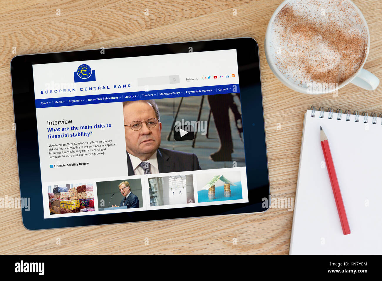 La Banque Centrale Européenne Site sur un iPad tablet device qui repose sur une table en bois à côté d'un bloc-notes et un crayon et une tasse de café (rédaction sur Banque D'Images