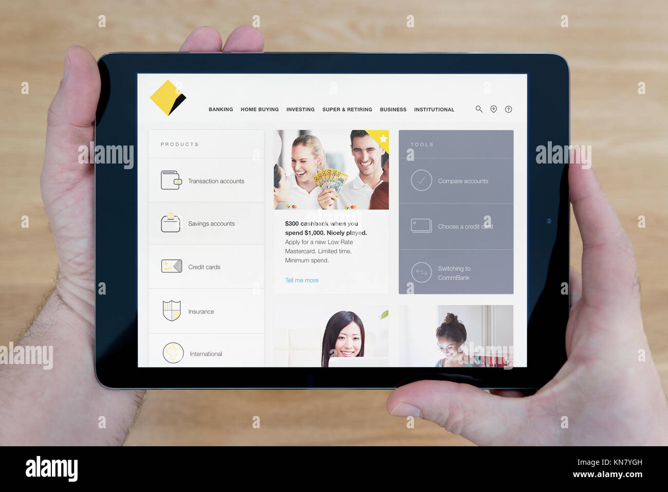 Un homme regarde la Commonwealth Bank site sur son iPad tablet device, tourné contre une table en bois page contexte (usage éditorial uniquement) Banque D'Images