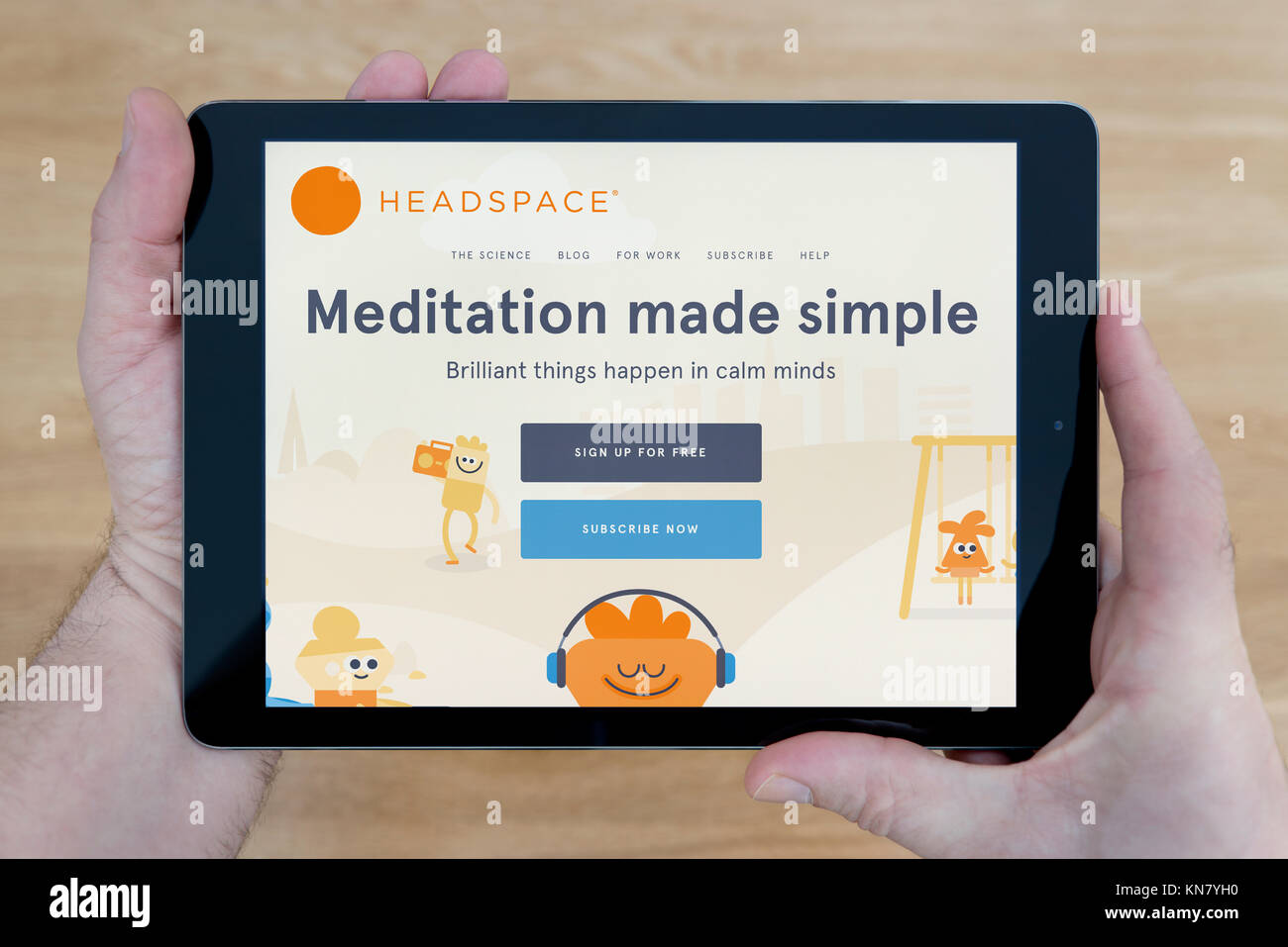 Un homme regarde le site web de l'espace de méditation sur son iPad tablet device, tourné contre une table en bois page contexte (usage éditorial uniquement) Banque D'Images