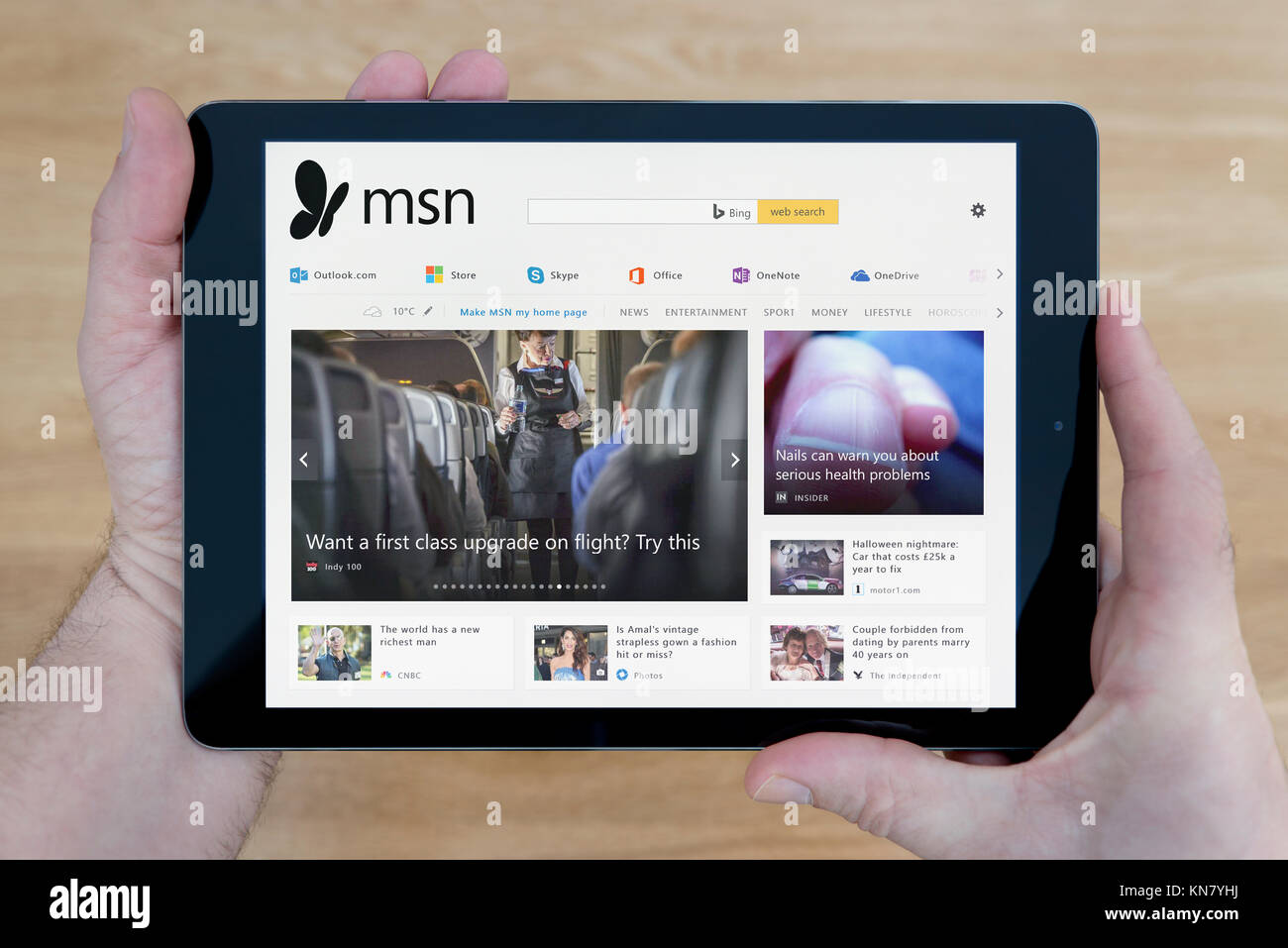 Un homme se penche sur le site Web MSN sur son iPad tablet device, tourné contre une table en bois page contexte (usage éditorial uniquement) Banque D'Images