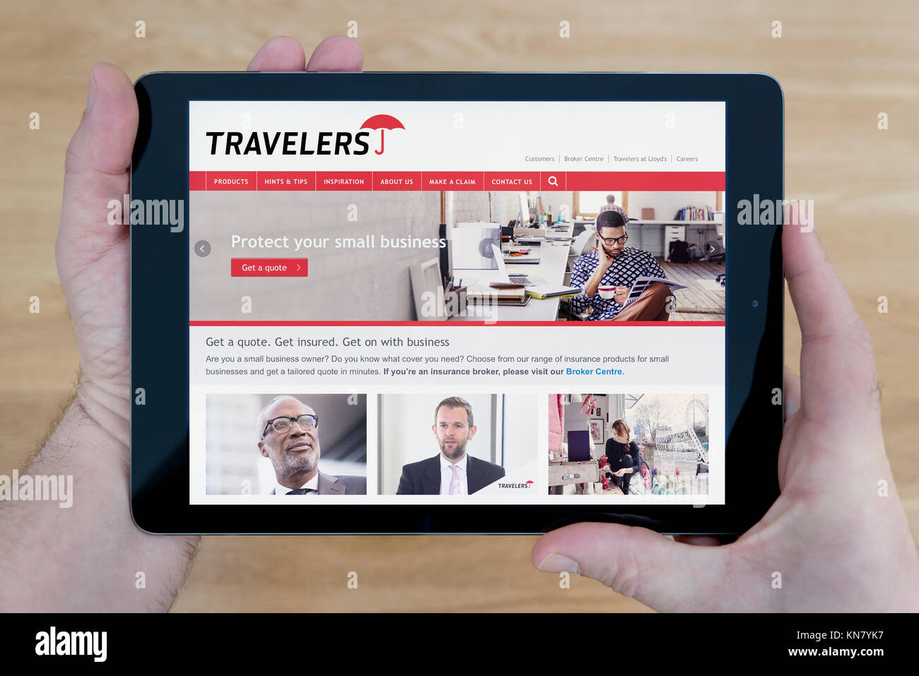 Un homme regarde les voyageurs site sur son iPad tablet device, tourné contre une table en bois page contexte (usage éditorial uniquement) Banque D'Images