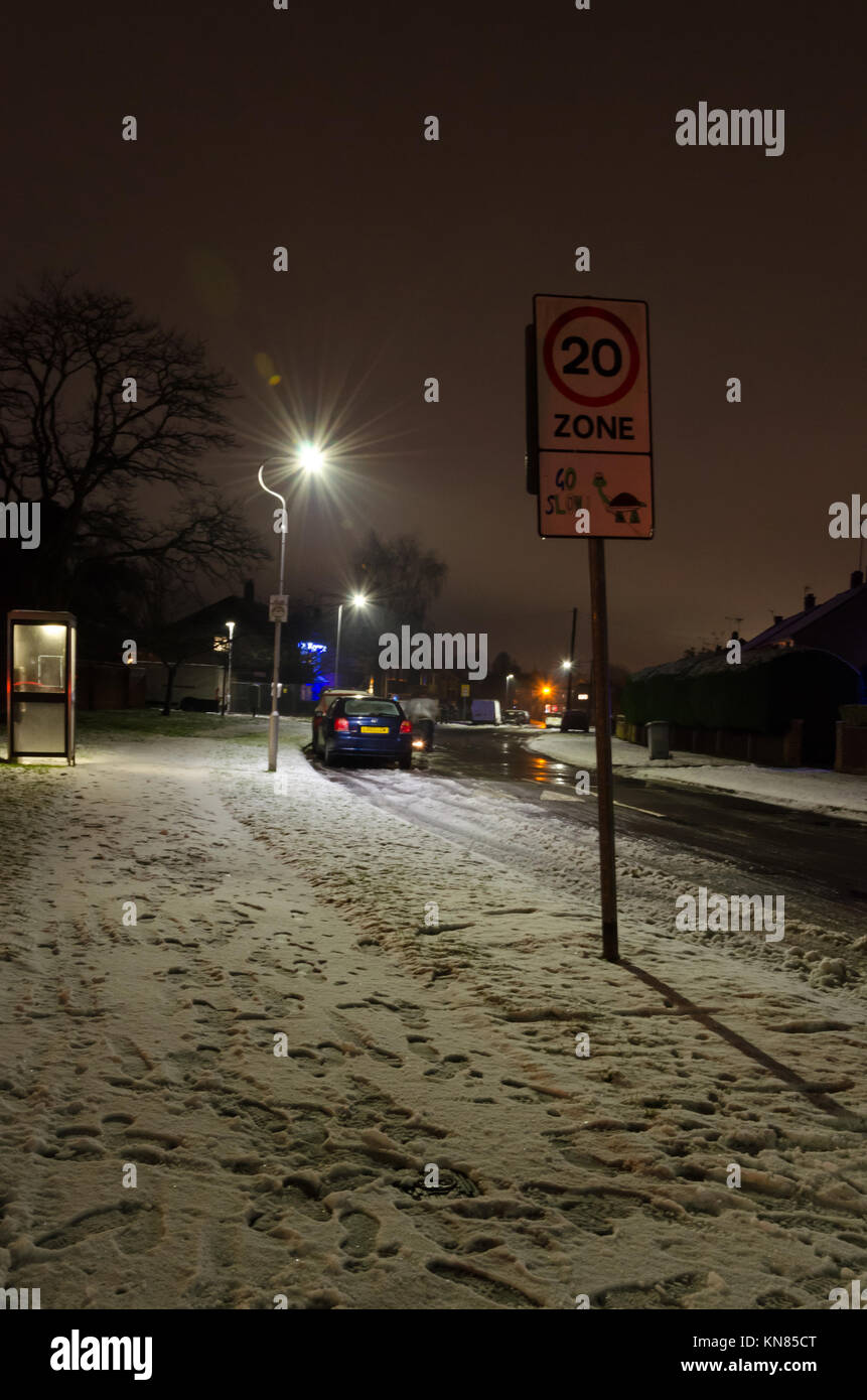 Une rue de banlieue vu la nuit après une journée de neige qui a laissé les trottoirs couverts de neige mais la route a disparu. Banque D'Images