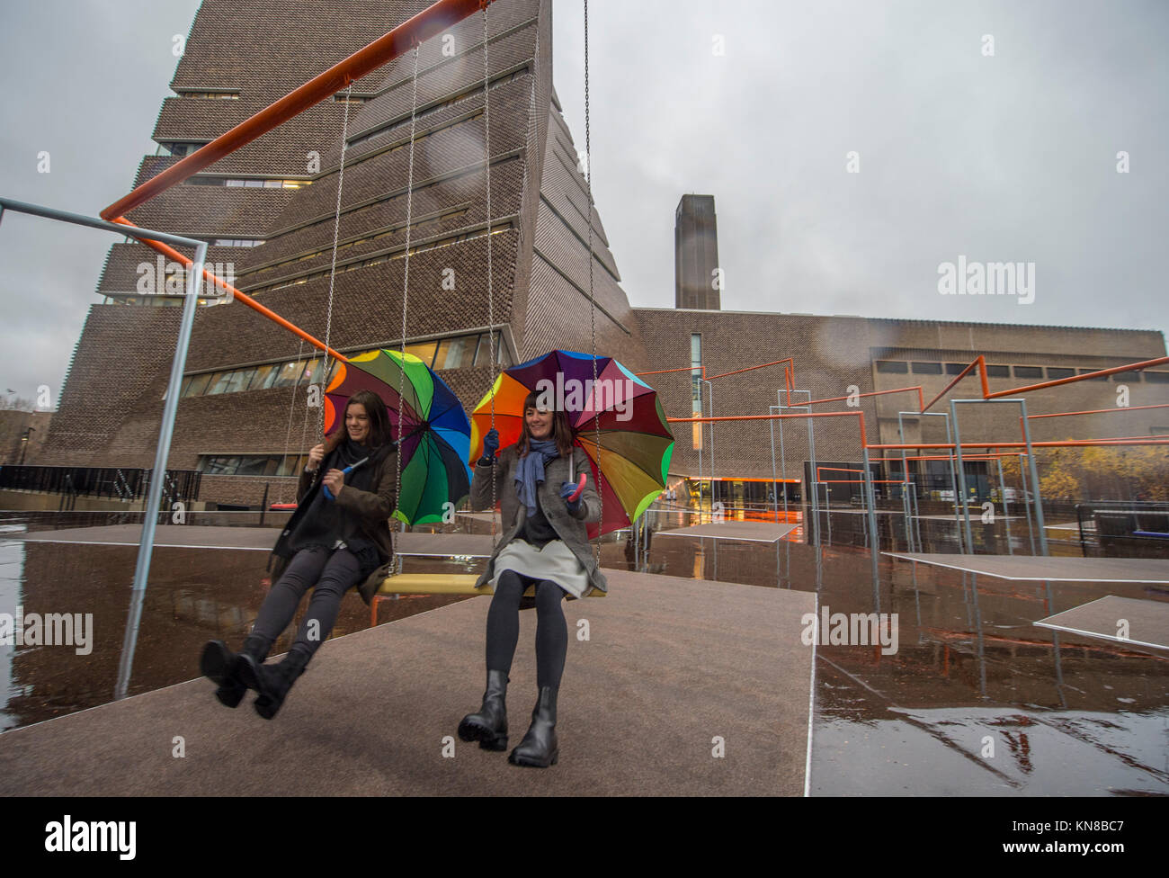 Tate Modern, Londres, Royaume-Uni. 11 Décembre, 2017. 11 Balançoires ont été installés à l'extérieur du bâtiment de la galerie Blavatnik, dans le cadre d'une installation interactive à grande échelle par le Danois SUPERFLEX collective. Un Deux Trois Swing ! Hyundai est la première commission d'étendre au-delà de la Turbine Hall et dans le paysage extérieur. L'installation à grande échelle dispose de onze sièges 3 balançoires dans le contexte de l'emblématique bâtiment de la Tate Modern avec des membres de la communauté locale appréciant les balançoires pour la première fois en pluie torrentielle. Credit : Malcolm Park/Alamy Live News. Banque D'Images