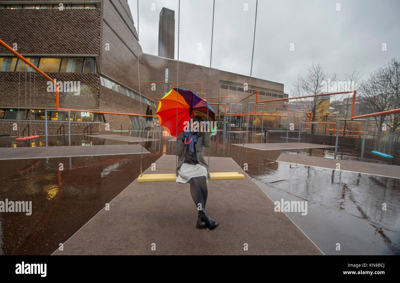 Tate Modern, Londres, Royaume-Uni. 11 Décembre, 2017. 11 Balançoires ont été installés à l'extérieur du bâtiment de la galerie Blavatnik, dans le cadre d'une installation interactive à grande échelle par le Danois SUPERFLEX collective. Un Deux Trois Swing ! Hyundai est la première commission d'étendre au-delà de la Turbine Hall et dans le paysage extérieur. L'installation à grande échelle dispose de onze sièges 3 balançoires dans le contexte de l'emblématique bâtiment de la Tate Modern avec des membres de la communauté locale appréciant les balançoires pour la première fois en pluie torrentielle. Credit : Malcolm Park/Alamy Live News. Banque D'Images