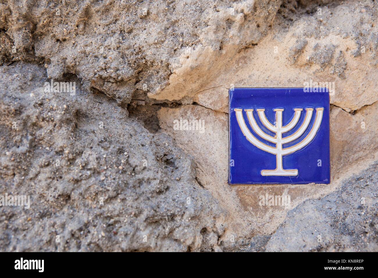 Carreaux émaillés sur mur de pierre avec symbole menorah marquant l'ancien quartier juif, Toledo, Espagne. Banque D'Images