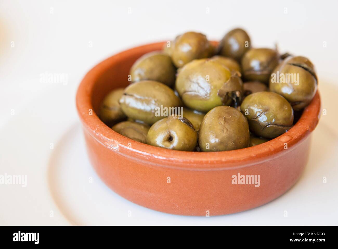 Green olives marinées concassées dans un bol d'argile. Apéritif traditionnel portugais. Banque D'Images