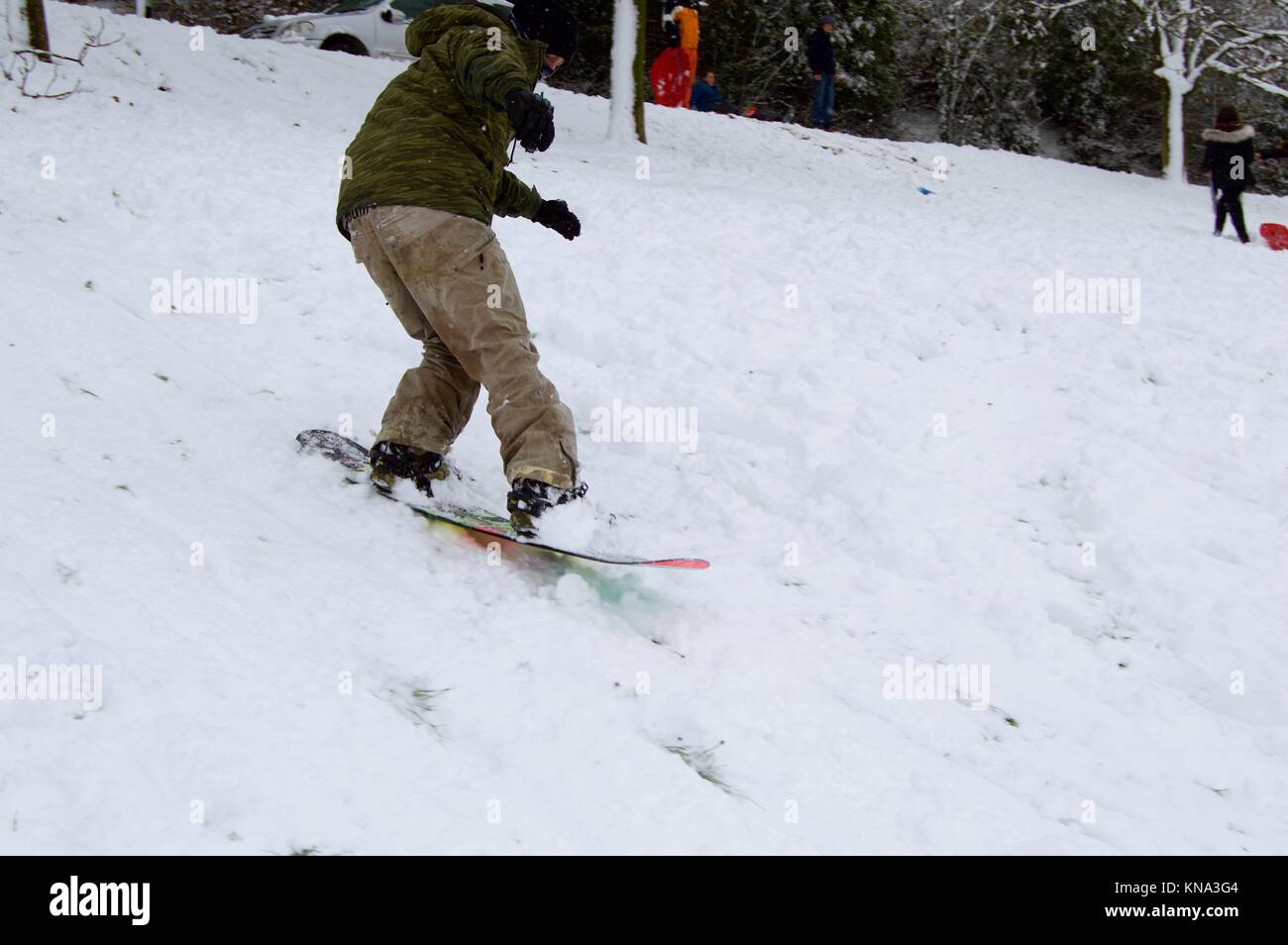Les enfants et les adultes bénéficiant d'une forte chute de neige par le snowboard et la luge en bas de la colline en vif des champs, Hemel Hempstead, Hertfordshire Banque D'Images