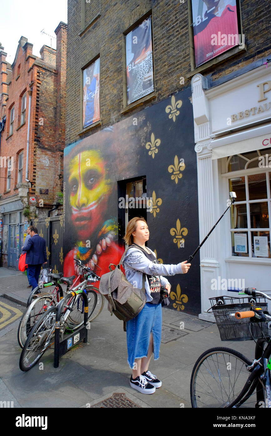 Woman taking photo à l'aide de bâton selfies à Shoreditch, London, England, UK Banque D'Images