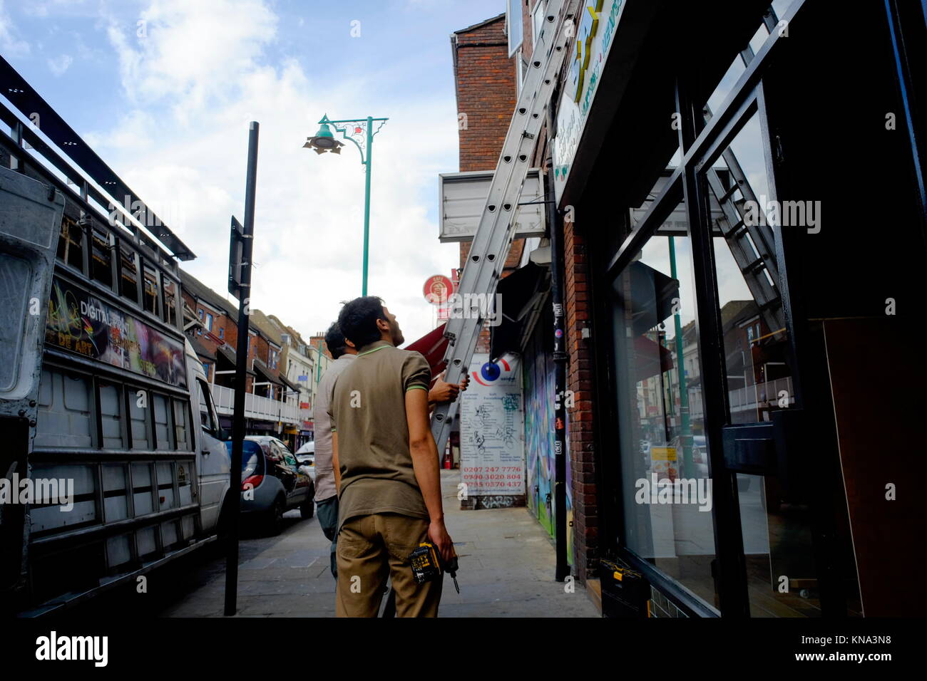 Des ouvriers par une échelle à l'extérieur de l'atelier à Shoreditch, London, England, UK Banque D'Images