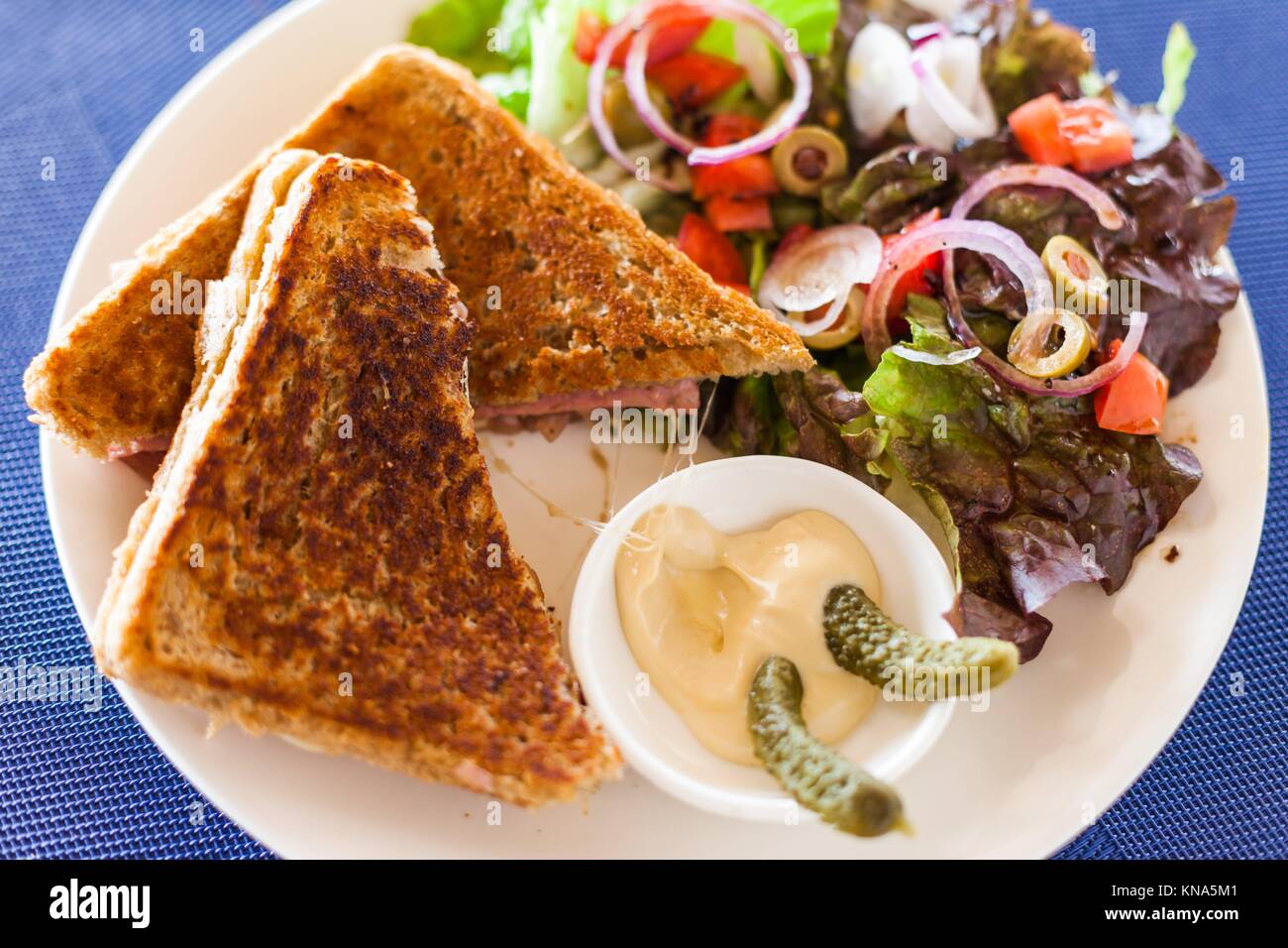 Croque-monsieur au sandwich avec salade et oignons caramélisés dans un café. Banque D'Images