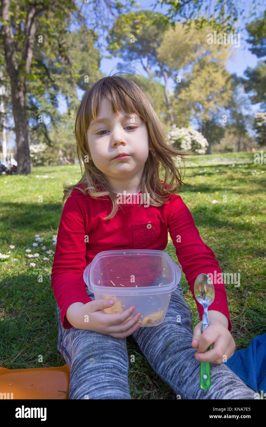 Trois ans, l'enfant blond avec chemise rouge et un pantalon gris, manger de  la salade de pâtes avec une cuillère de plastique, que pique-nique, assis  sur vert Photo Stock - Alamy
