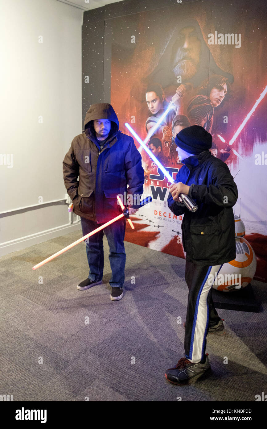 Les fans de Star Wars jouer agissant avec sabres laser en face d'une affiche de la Guerre des Étoiles Le dernier Jedi dans le film's pop-up store dans le centre-ville de Toronto, Canada. Banque D'Images