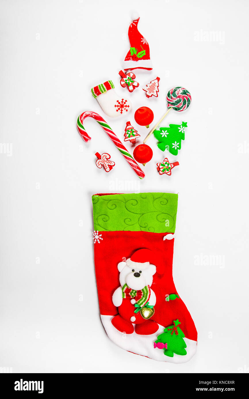Noël arrière-plan avec une chaussette à partir de laquelle les cadeaux éparpillés, des bonbons, des décorations du Nouvel An jouets sur un fond blanc. Le concept de la publicité, de la shopp Banque D'Images