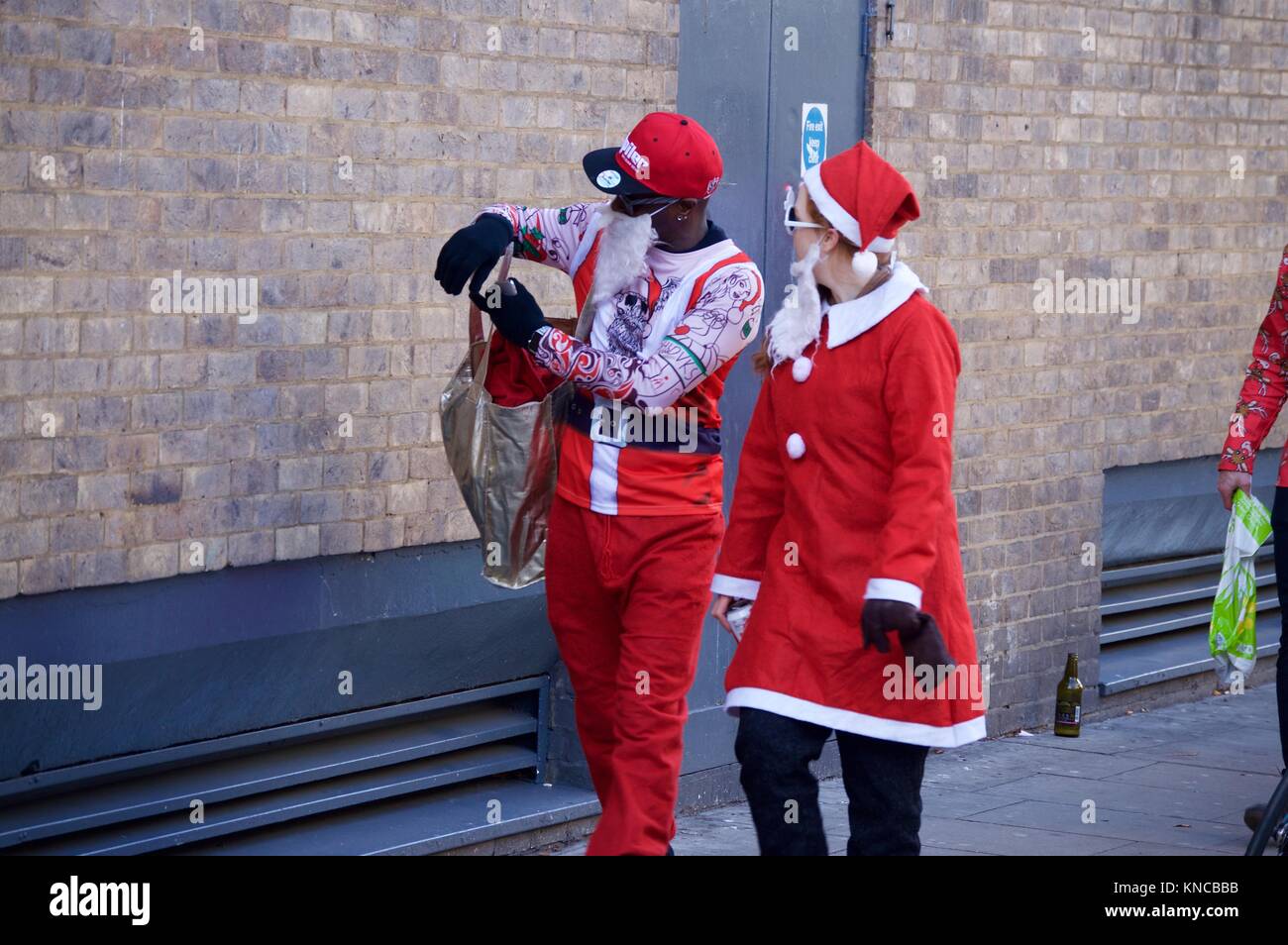 Flash mob habillé en père Noël marche à travers Londres, buvant, et se réjouissant pour Santacon 2017 dans le nord de Londres, King's Cross area Banque D'Images