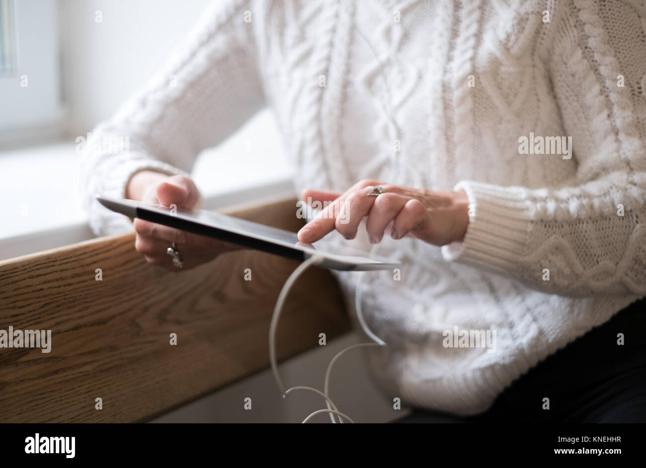 Femme appuyée contre un mur à l'aide d'une tablette numérique Banque D'Images