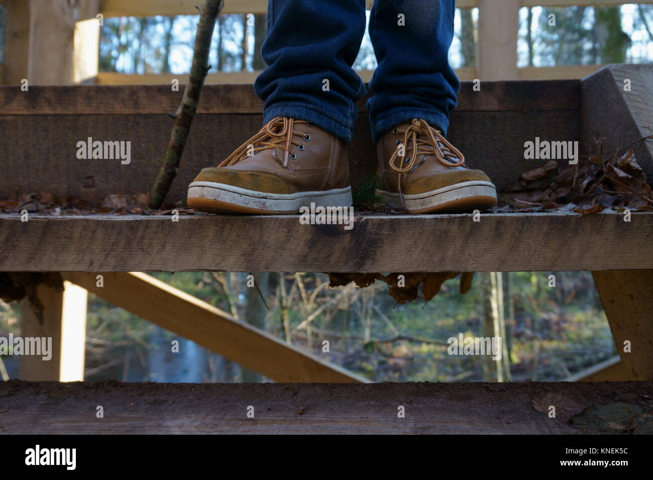 Enfant Garçon habillé de bleu jans et brown shoess, debout sur une tour d'observation des mesures à l'automne parc. Banque D'Images