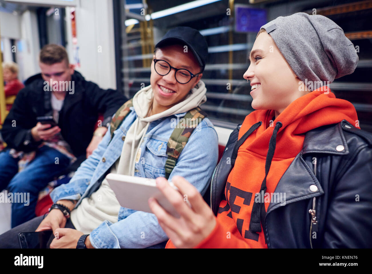 Jeune couple en attente dans la station de métro looking at smartphone Banque D'Images