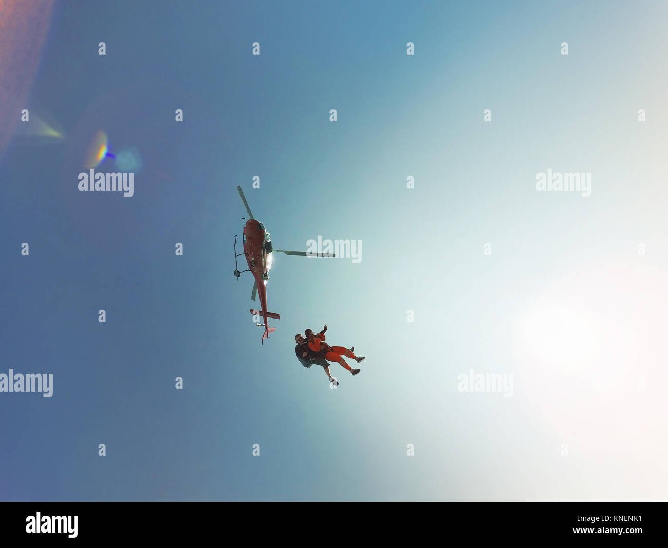 Low angle view of Tandem saut en parachute d'un hélicoptère contre ciel bleu ensoleillé Banque D'Images