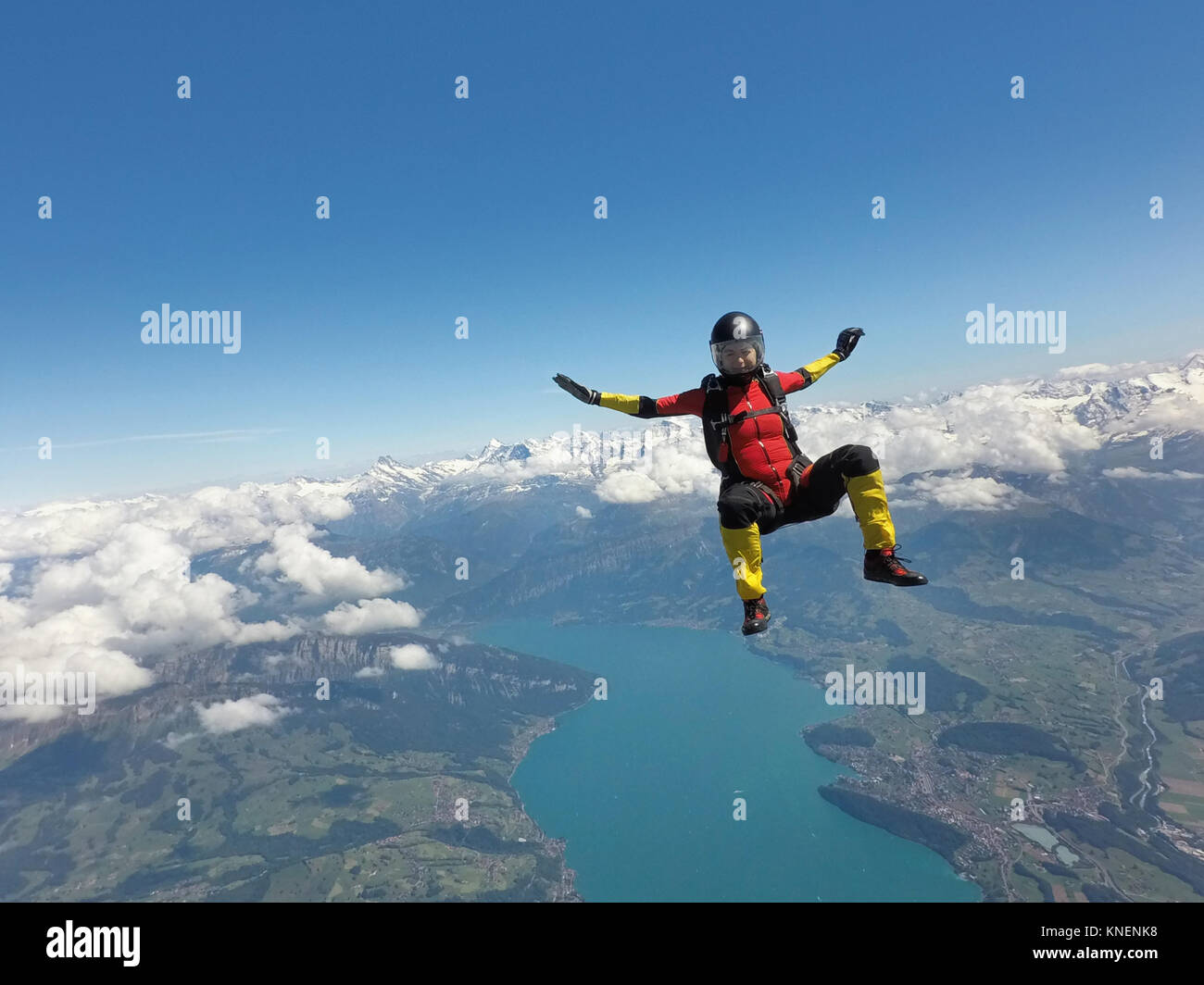 Parachutiste féminin assis en chute libre au-dessus des nuages et le lac Banque D'Images