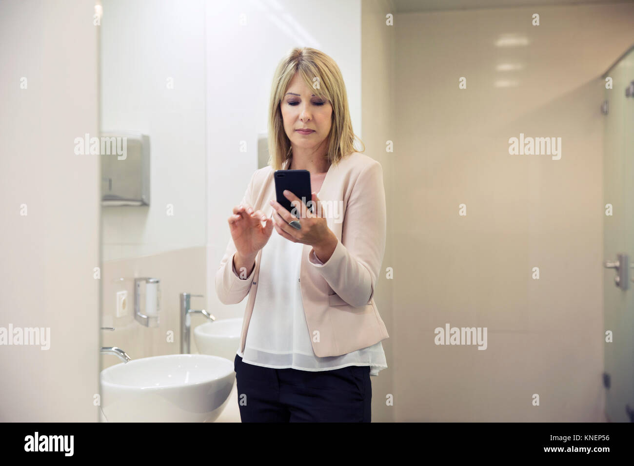 Woman using smartphone dans la salle de bains Banque D'Images