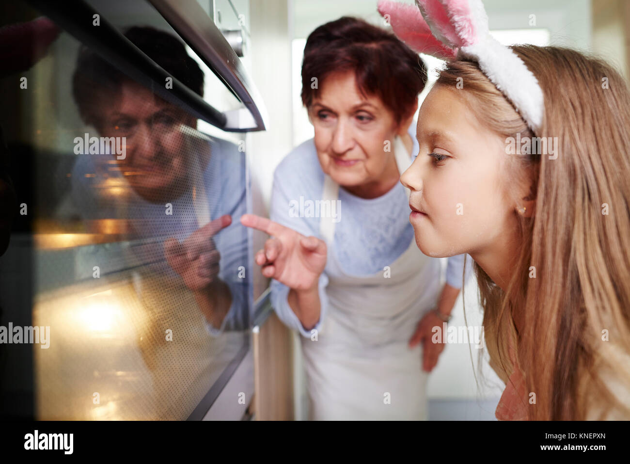 Grand-mère et fille regardant dans la cuisine four biscuits de Pâques Banque D'Images
