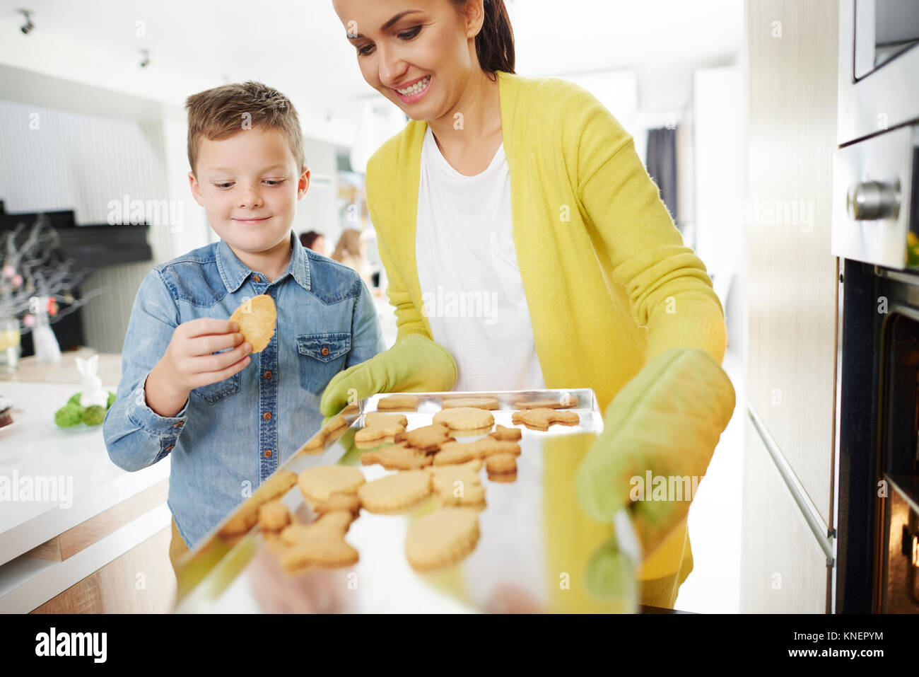 Garçon pinçant de biscuit de pâques la mère de cuisson dans la cuisine Banque D'Images