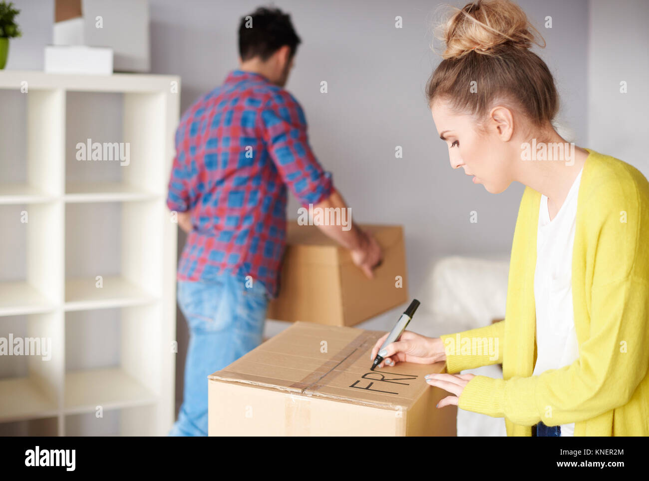 Jeune couple déménager, jeune femme boîte en carton d'étiquetage Banque D'Images