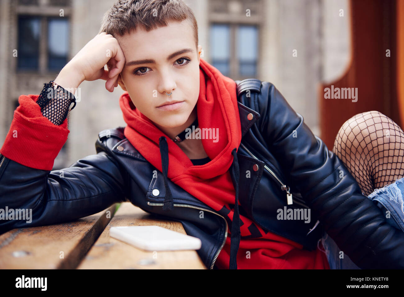 Portrait de jeune femme cool avec les cheveux courts au banc de la ville Banque D'Images