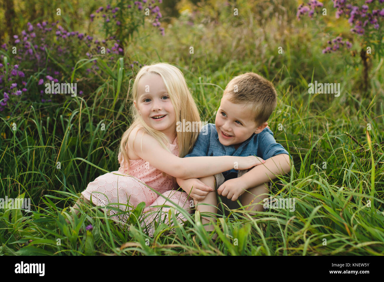 Garçon et fille assise dans l'herbe haute ensemble Banque D'Images