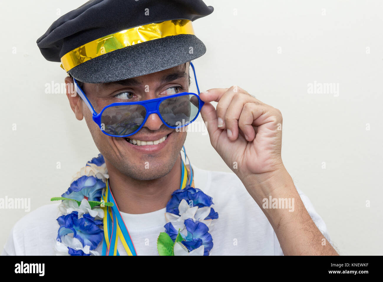L'homme noir est habillé comme un capitaine ou pilote. Il porte des lunettes  de soleil et collier hawaïen à un carnaval partie. Il est à la recherche  sur le côté et sourit