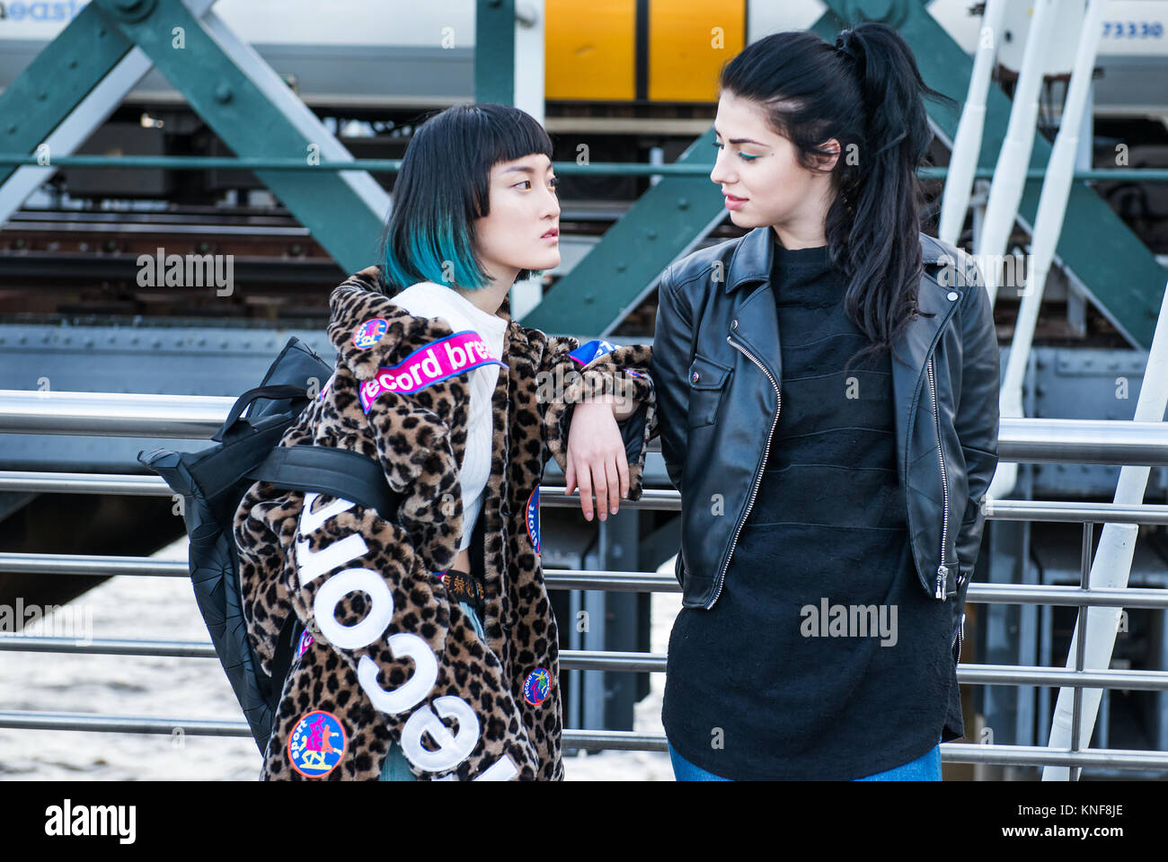 Deux jeunes femmes élégantes appuyé contre la main courante sur la passerelle du millénaire, London, UK Banque D'Images