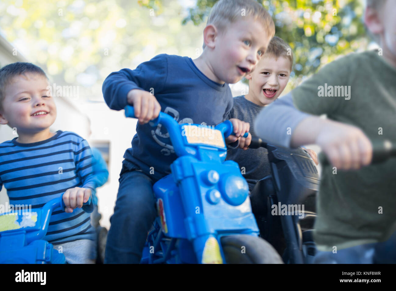 Les garçons à l'âge préscolaire course motos push in garden Banque D'Images