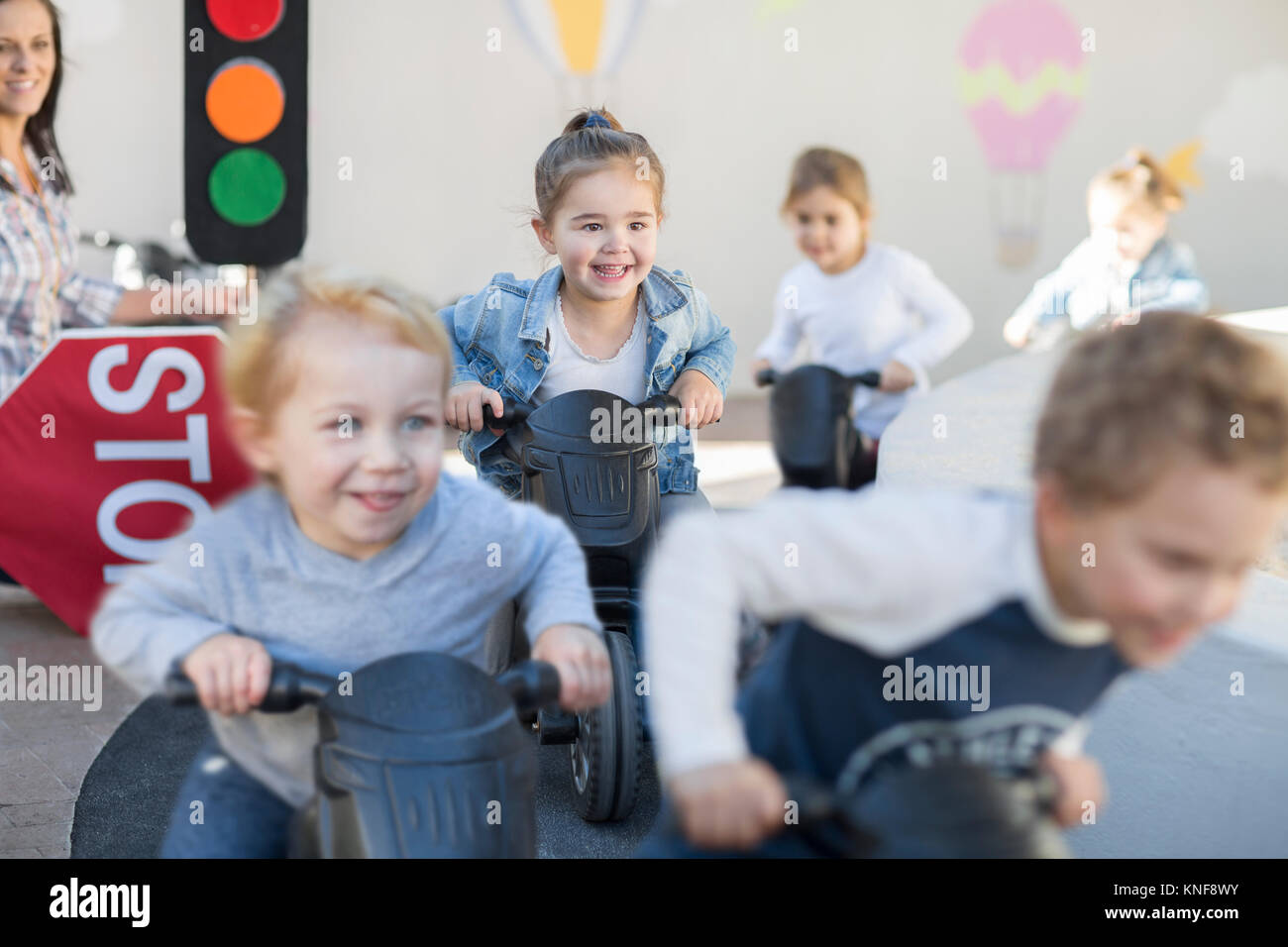 Les garçons et les filles à l'éducation préscolaire, course motos push in garden Banque D'Images