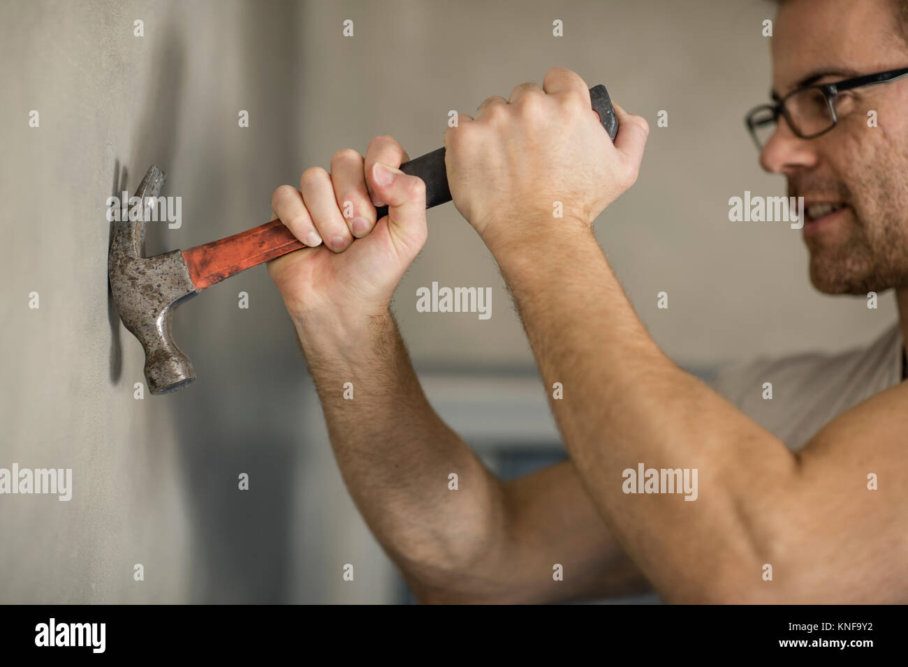 Man taking nail de mur, à l'aide d'un marteau Banque D'Images